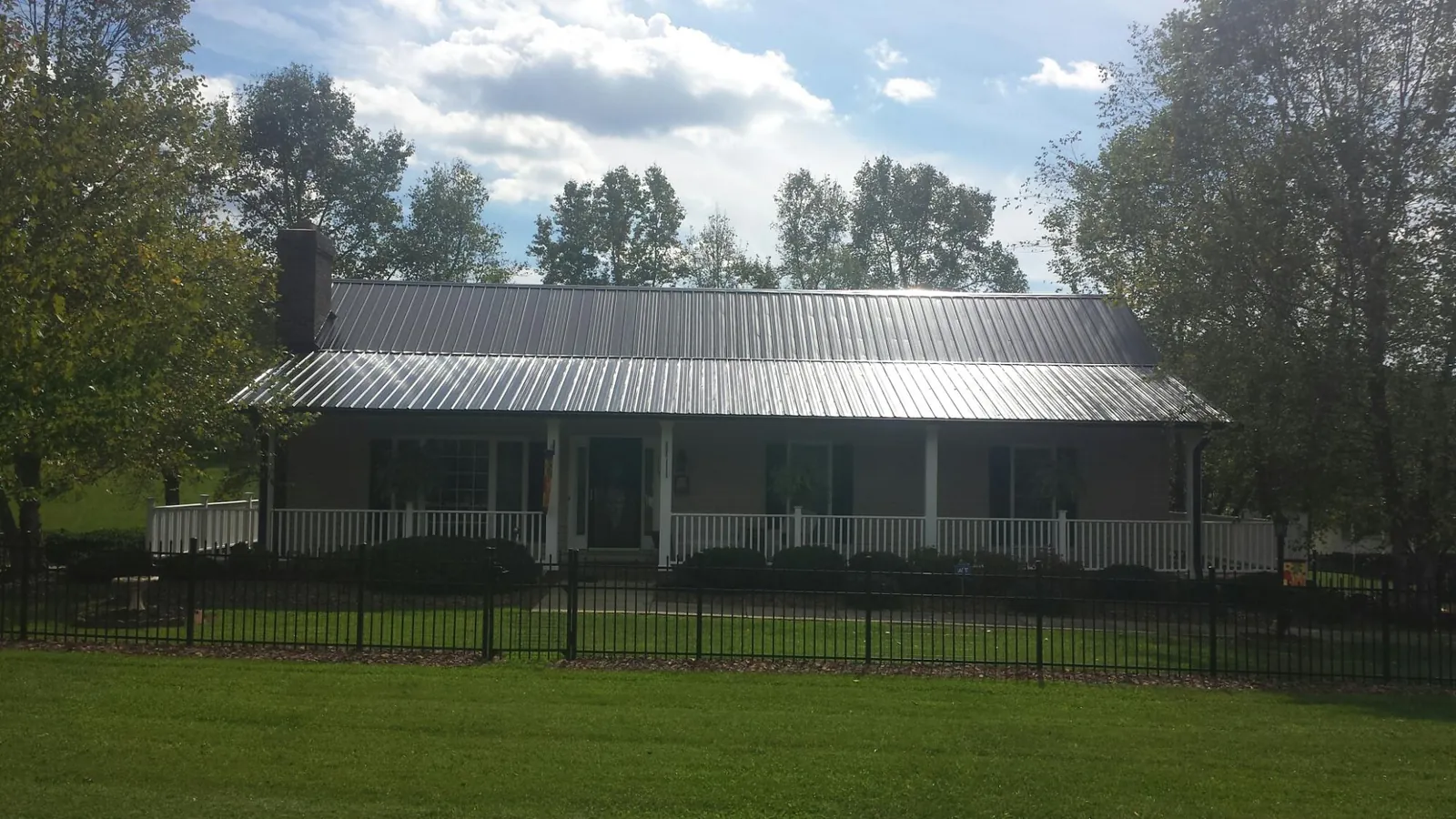 Gray metal roof on a brick ranch with a full width front porch — Gutter Guard Installation work by our crew in Rose Hill